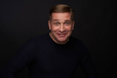 Siyah arka planda 40 yaşında beyaz bir adamın stüdyo portresi.