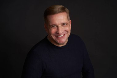 Siyah arka planda 40 yaşında beyaz bir adamın stüdyo portresi.