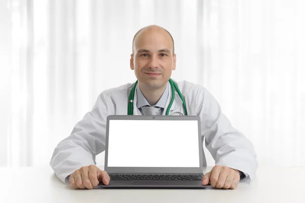 Bonito doktor sentado em uma mesa com laptop — Fotografia de Stock