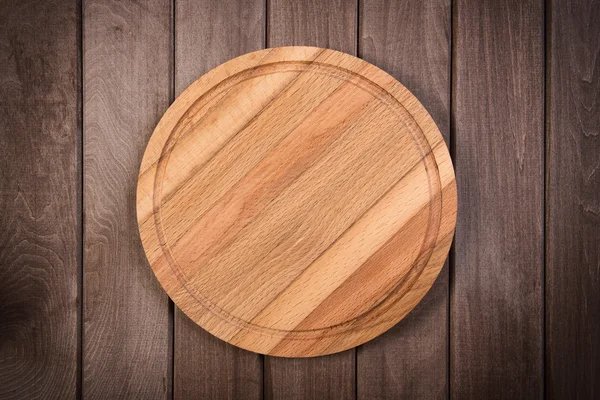 Cutting board on dark wooden background — Stock Photo, Image