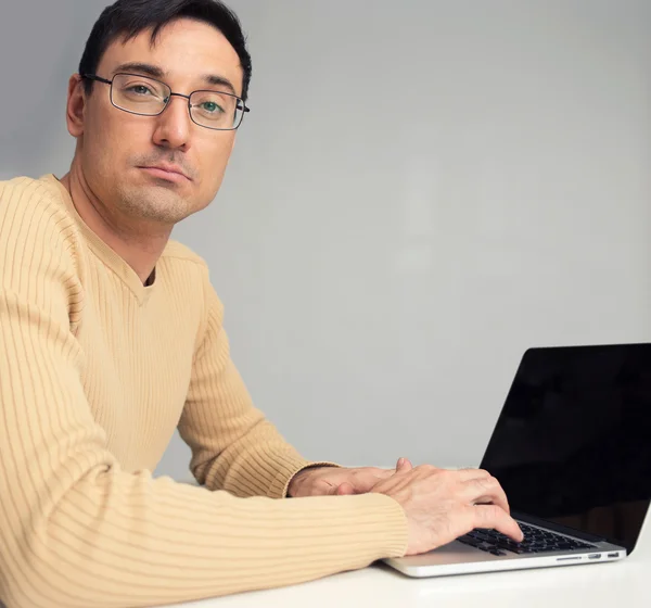 Чоловік сидить за столом, працює на портативному комп'ютері — стокове фото