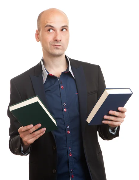 Homem confuso segurando dois livros em mãos — Fotografia de Stock