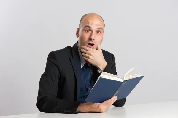 Homem careca surpreso lê um livro — Fotografia de Stock