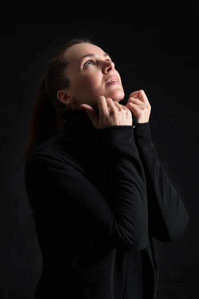 Brünette Frau, die in der Dunkelheit aufblickt. Beten — Stockfoto