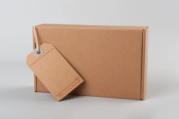 Parcel. cardboard box with blank tag — Stock Photo, Image