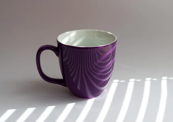 Cup on a white table with shadows from the blinds incident — Stock Photo, Image
