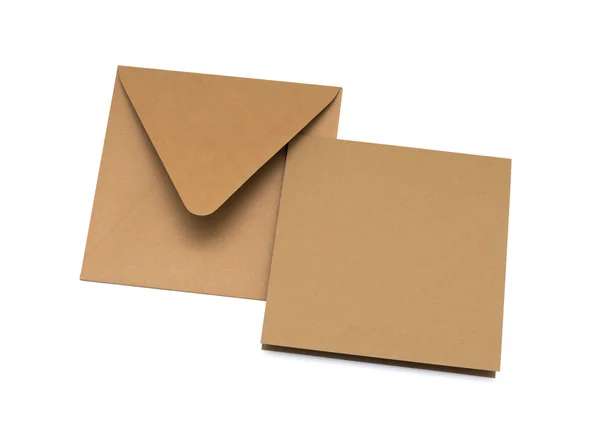 Brauner Umschlag mit einer leeren Karte über weißem Papier — Stockfoto