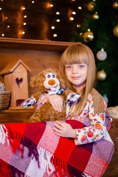 Маленькая девочка держит игрушку возле рождественской елки — стоковое фото