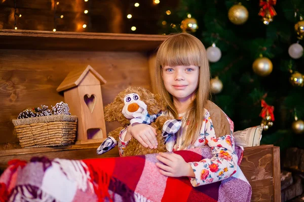 Menina segurando brinquedo perto da árvore de natal — Fotografia de Stock