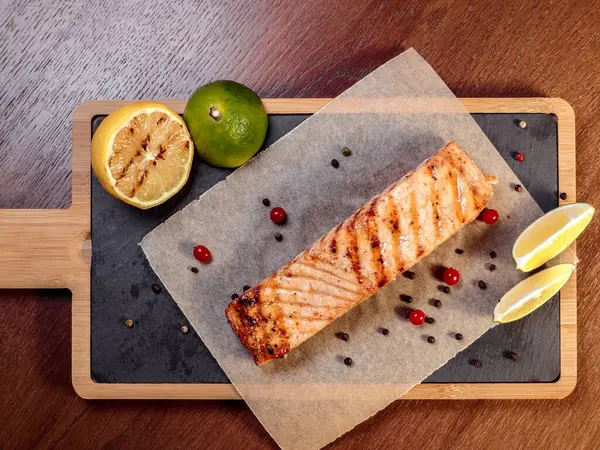 Grilled salmon on coals with lemon on a wooden board. — Stock Image Grilled Salmon Coals Lemon Wooden Board Royalty Free Stock Photos