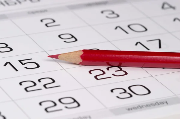 Красный карандаш над календарем — стоковое фото