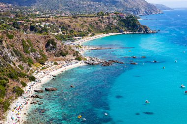 Turkuaz körfezi, kumlu sahil, yeşil dağlar ve bitkiler, mavi gökyüzü beyaz bulutlar arka plan, uçurum platformu Capo Vaticano Cape, Calabria, Güney İtalya.