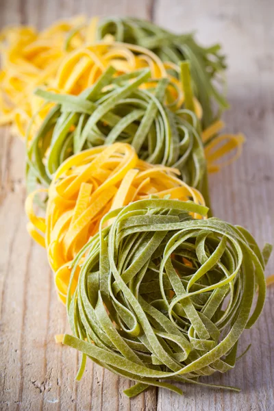 Yellow and green uncooked pasta tagliatelle — Stock Photo, Image