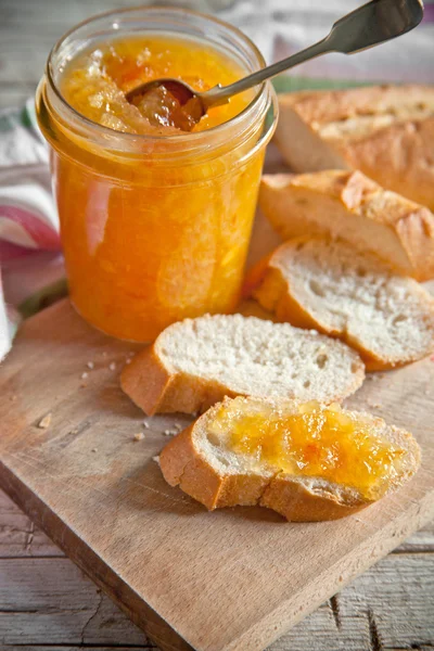 Orange jam in a glass jar and bread — Stock Photo, Image