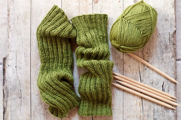 Wool green legwarmers, knitting needles and yarn — Stockfoto