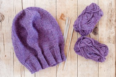 wool purple hat, knitting needles and yarn 