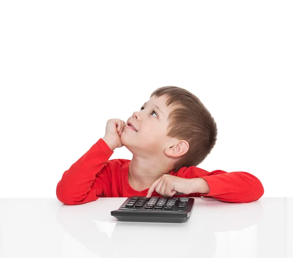 The five-year boy sitting at a white table and presses the button calculator — Stock Photo, Image