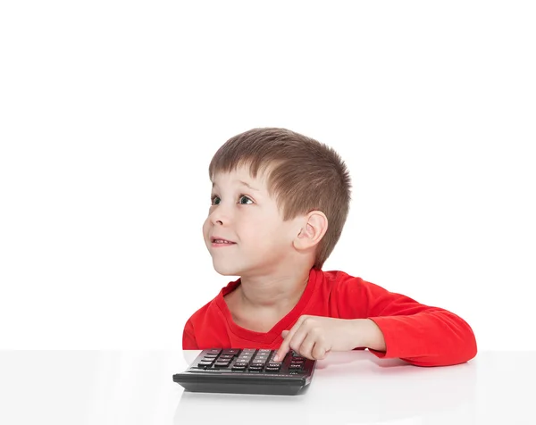 Pięcioletni chłopiec siedzący przy stole biały i naciśnie przycisk Kalkulator — Zdjęcie stockowe