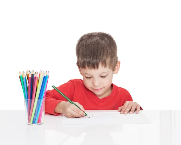 П'ятирічний хлопчик сидить за білим столом і малює олівці — стокове фото