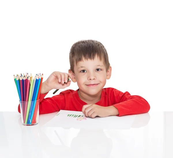 Le garçon de cinq ans s'assoit à une table blanche et dessine des crayons — Photo