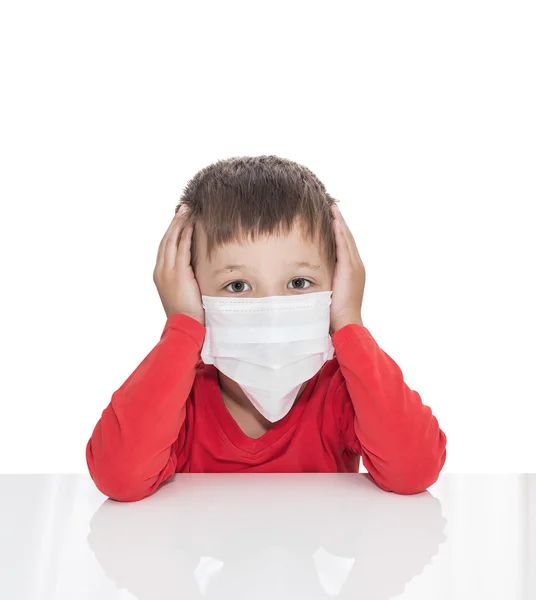 The sick five-year-old boy sits at a white table with medicine healthcare mask — Stock Photo, Image