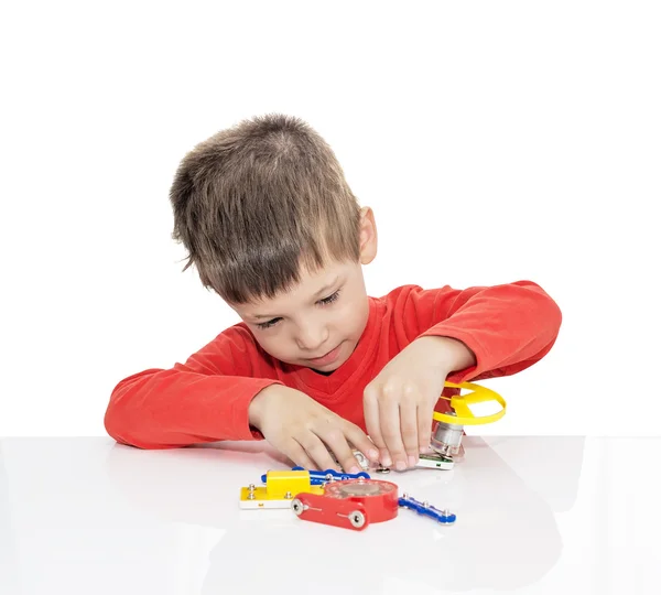 П'ятирічний хлопчик сидить за білим столом і грає електронного дизайнера — стокове фото