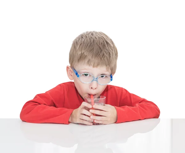 П'ятирічний хлопчик сидить за білим столом і п'є воду — стокове фото