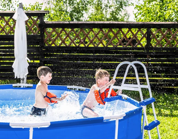 夏天，六岁的双胞胎在框架游泳池里玩耍 — 图库照片