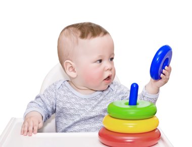 Çocuk, bir oyuncakla küçük tablo üzerinde beyaz izole bir piramit mu