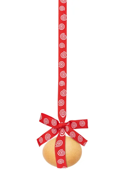 De Easter egg, hangt af van een lint, met rood met spiralen boog, geïsoleerd op een witte achtergrond — Stockfoto