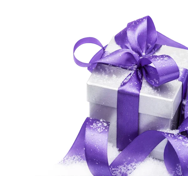 Confezione regalo con fiocco lilla sulla neve isolata sul bianco — Foto Stock