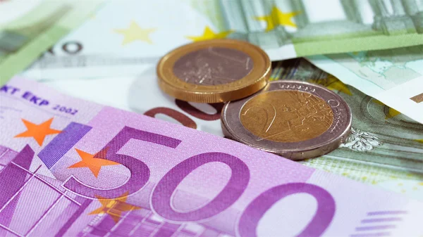 Two Euro coins over bank notes — Stock Photo, Image