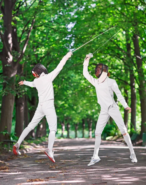 Two rapier fencer women fighting over park alley, attacking each — Stock Photo, Image