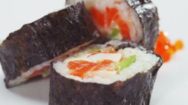 Suşi rulo somon, avokado ve beyaz üzerinde dönen havyar ile