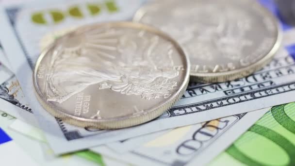 Серебряно-американские долларовые монеты на фоне различных банкнот — стоковое видео