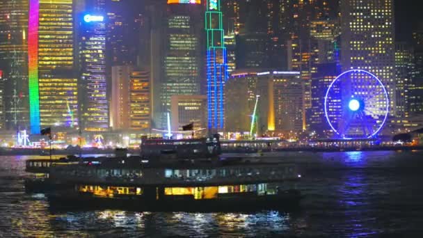 Uitzicht op de waterkant van Hong Kong City 's nachts met levendige verlichting en schepen — Stockvideo