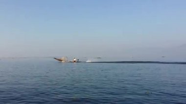 Inle Gölü'nü geçen teknedeki balıkçı. Myanmar'ın doğa manzarası arka planı