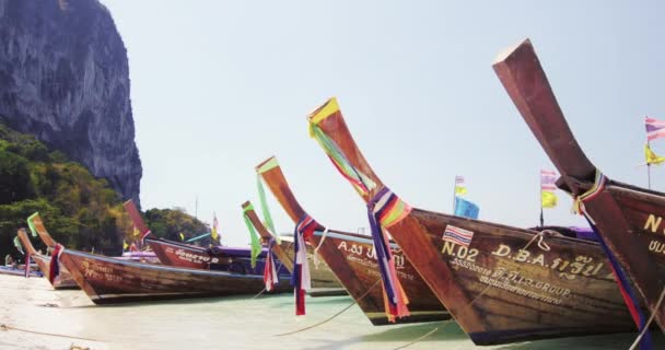 Barcos turísticos tailandeses decorados com tiras coloridas na praia de areia do mar tropical — Vídeo de Stock