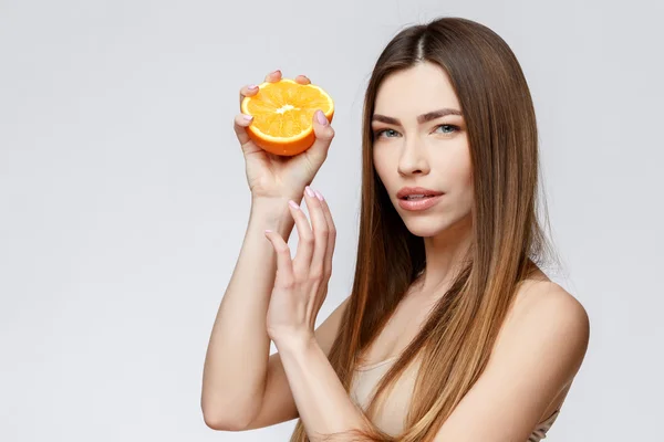 Piękna kobieta z czystą skórę świeżą, trzymając pomarańczowe — Zdjęcie stockowe