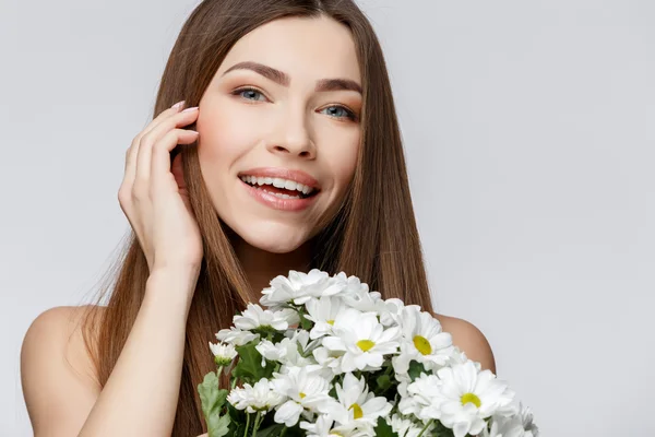 Vacker kvinna med ren fräsch hud håller blommor — Stockfoto