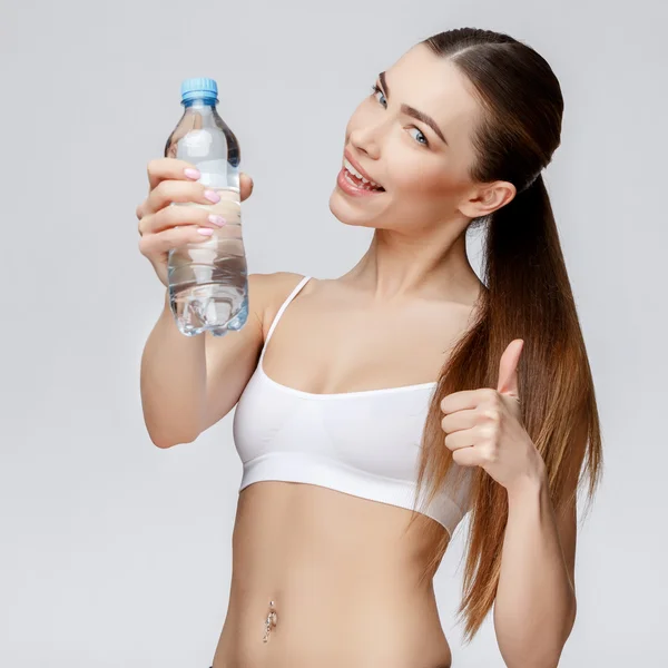 Mujer deportiva sobre fondo gris agua potable — Foto de Stock