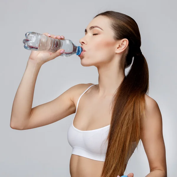 Mujer deportiva sobre fondo gris agua potable —  Fotos de Stock