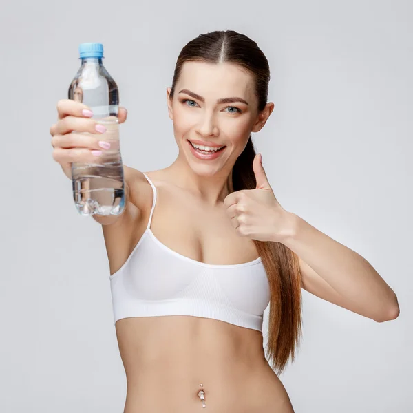Sportliche Frau vor grauem Hintergrund trinkt Wasser — Stockfoto