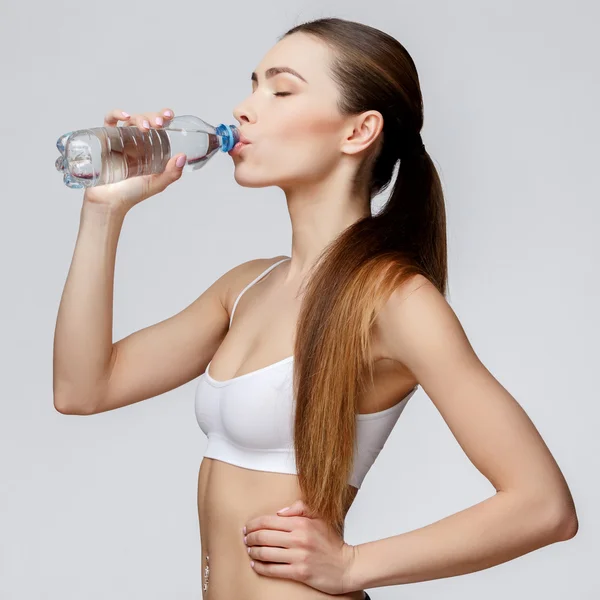 在灰色背景饮用水的运动型女人 — 图库照片