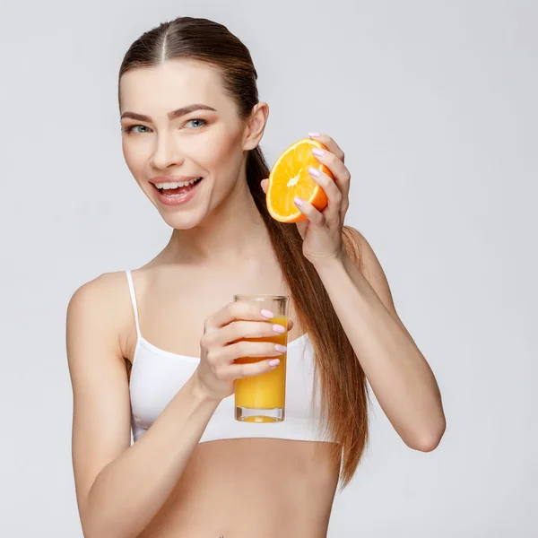 Спортивна жінка над сірим тлом тримає склянку апельсинового соку — стокове фото