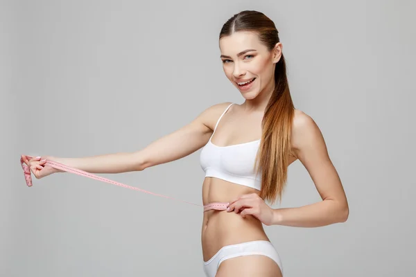 Schlank gebräunter Frauenkörper vor grauem Hintergrund — Stockfoto