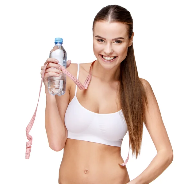 Attraente donna sorridente in possesso di bottiglia d'acqua isolata su bianco — Foto Stock