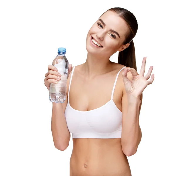 Attraente donna sorridente in possesso di bottiglia d'acqua isolata su bianco — Foto Stock