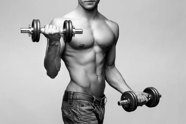 Shirtless fisiculturista segurando dumbell e mostrando seus braços musculares . — Fotografia de Stock