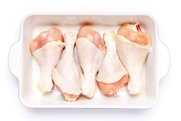 Rohe Hühnerkeulen in Auflaufform auf weißem Hintergrund — Stockfoto